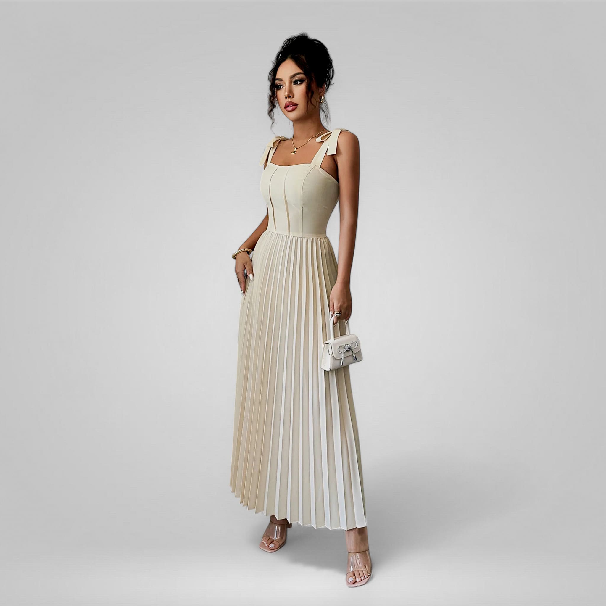Woman wearing a beige pleated dress on a gray background