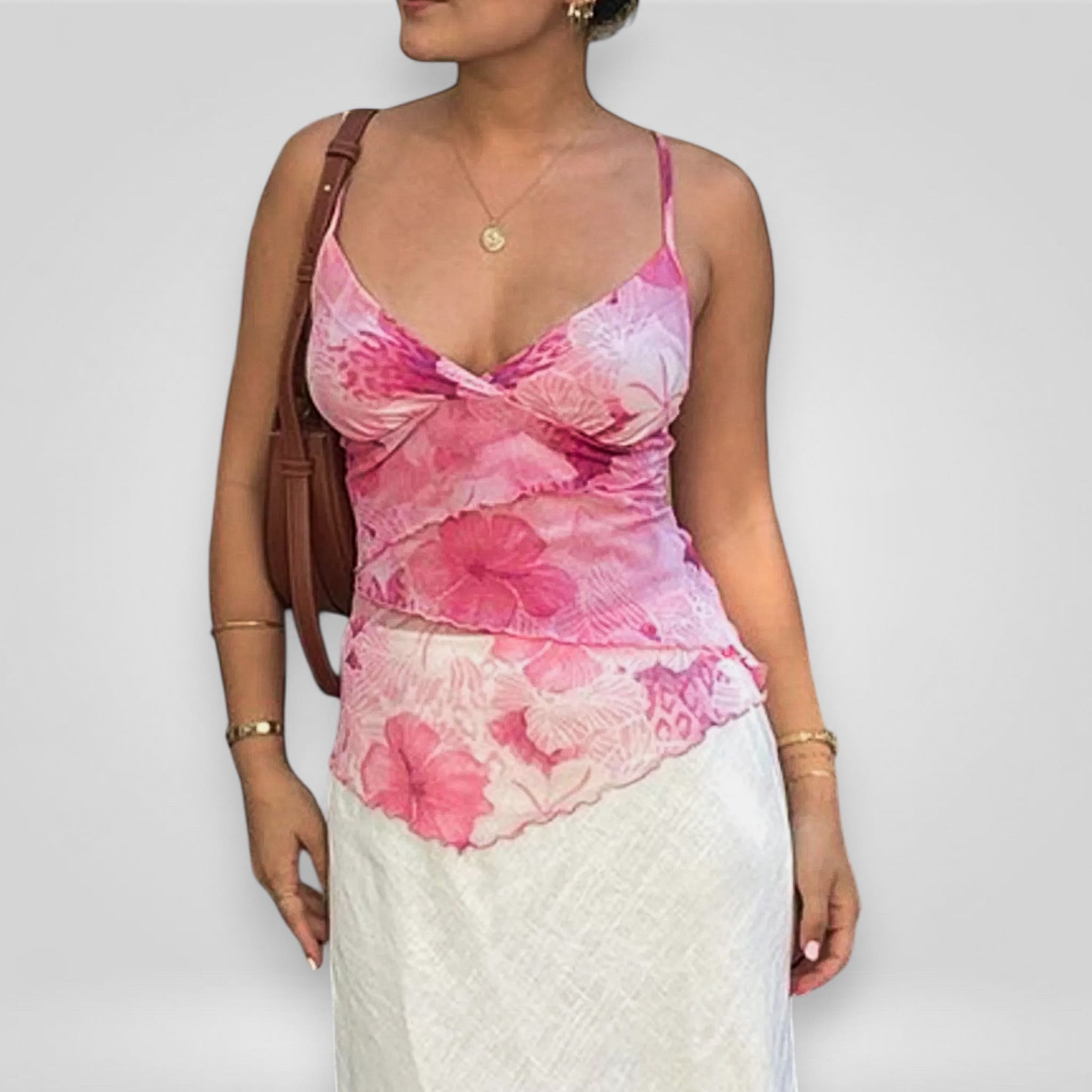 Woman wearing a pink floral top and white skirt against a plain background