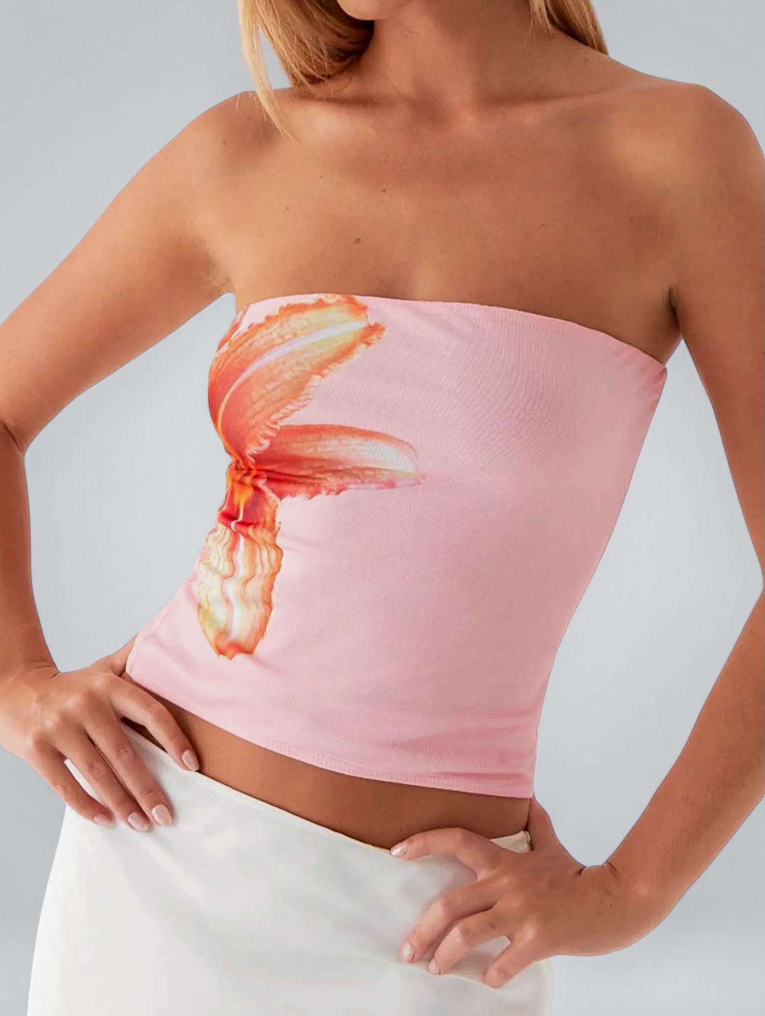 Woman wearing a pink strapless top with a graphic design on a plain background